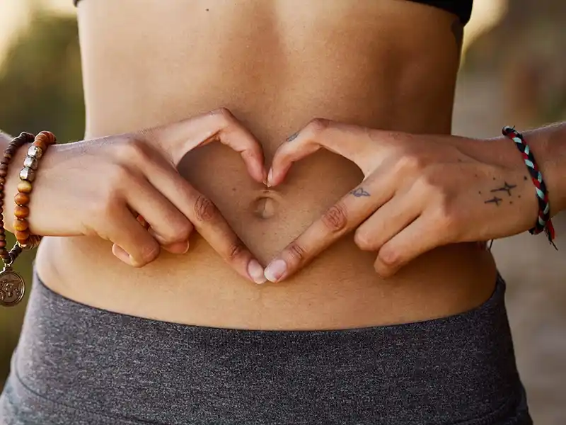 Una chica haciendo forma de corazón con los dedos. Imagen representativa de salud y fitoterapia.